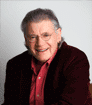 Head shot photo of author Peter E. Murphy smiling, with glasses, a red button-up shirt, and a dark blazer